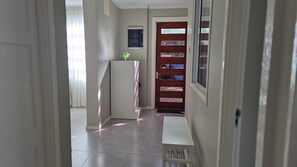 Un couloir avec un réfrigérateur, une porte dotée d’une fenêtre et un banc.