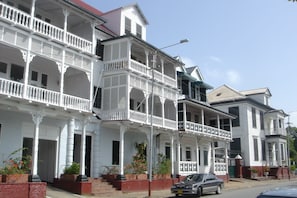 Une rangée de bâtiments blancs de style colonial, dotés de balcons, et un tramway.