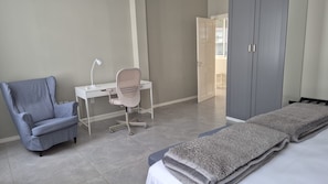 Une chambre d’hôtel avec un lit, un bureau, une chaise et une armoire.