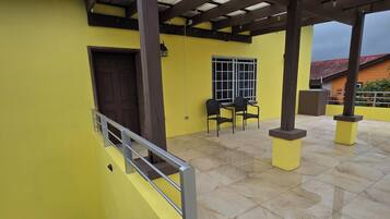 A covered outdoor area with a yellow wall, a door, and a window.