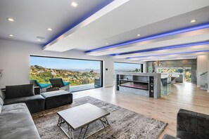 Een moderne woonkamer met een groot raam, een open haard en uitzicht op een stadsbeeld.