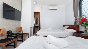 Ett hotellrum med två sängar, en tv, ett soffbord och ett fönster med gardiner.