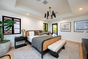 A modern bedroom with a large bed, bedside tables, a bench, and artwork on the walls. - Tower Vista By Alora Reserve (Beverly Hills)