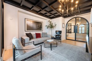 A modern living room with a sofa, armchairs, a coffee table, and a large painting. - Tower Vista By Alora Reserve (Beverly Hills)