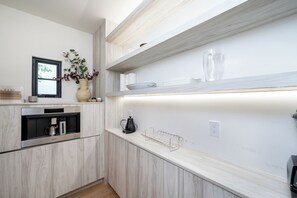 A modern kitchen with a built-in oven, a coffee machine, and a vase with flowers on the counter. - Tower Vista By Alora Reserve (Beverly Hills)