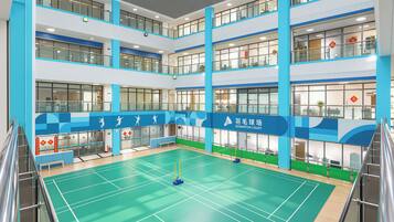 Una palestra al coperto per badminton su più livelli, con ringhiere in vetro e una combinazione di colori blu e bianco.