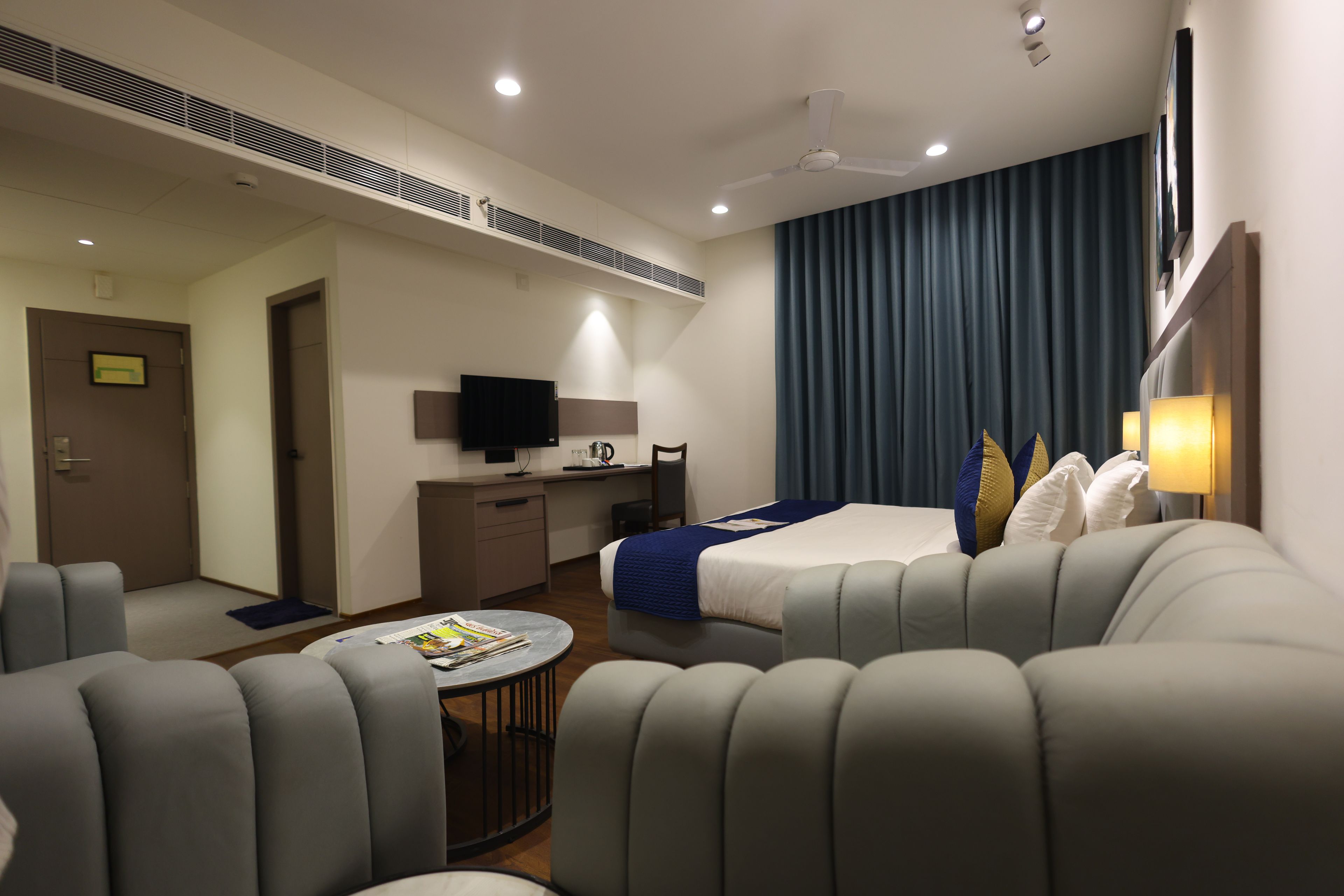 Een moderne hotelkamer met een bed, een bank, een bureau en een televisie.