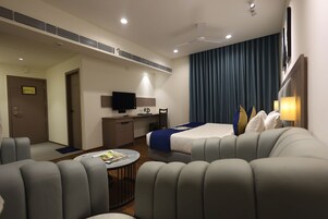 Una habitación de hotel moderna con cama, sofá, escritorio y televisor.