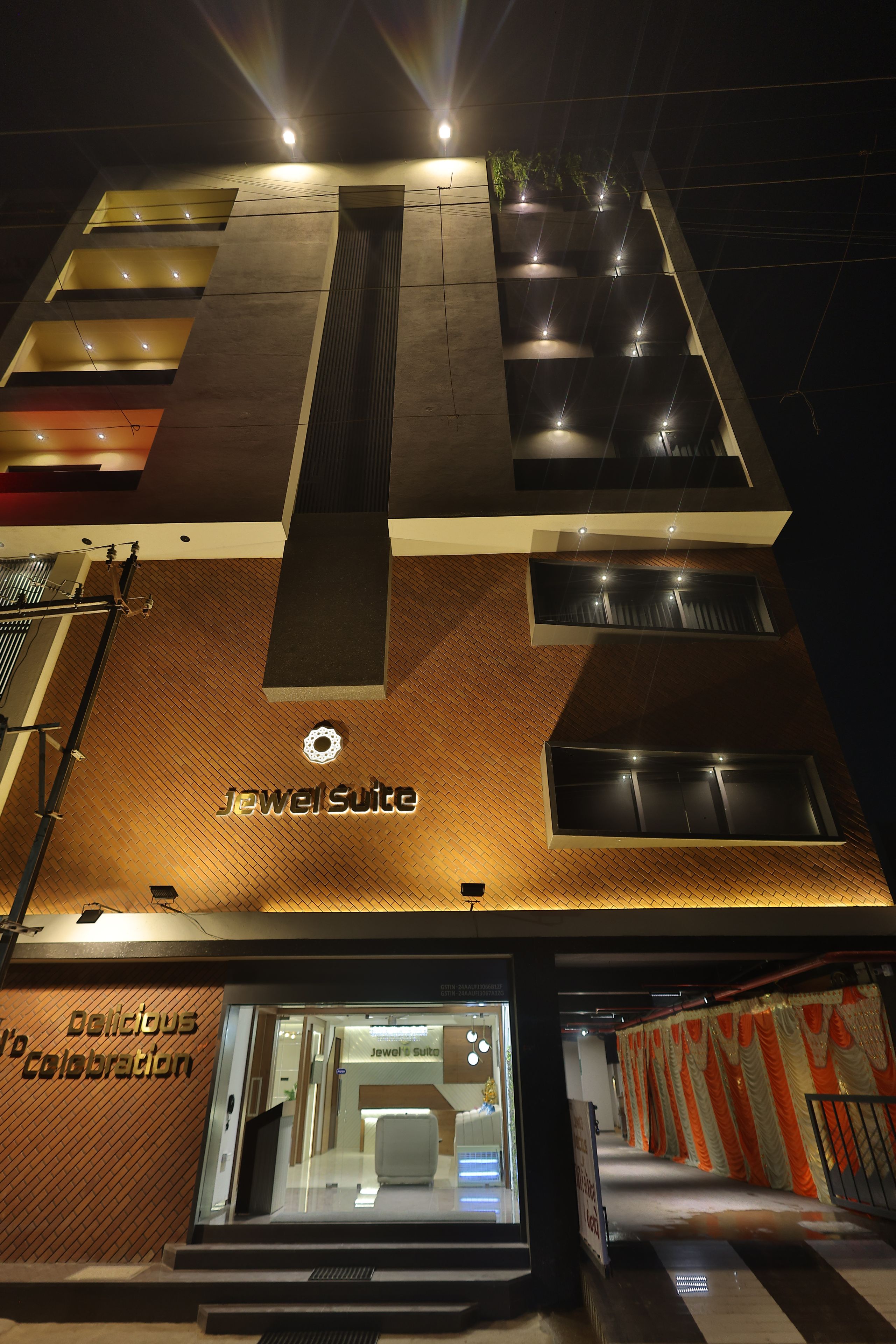 Een hotel met een modern design, met een opvallend bord 'Jewel Suite', een patroonvormig gevelontwerp en een goed verlichte entree.