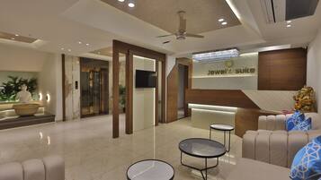 Een moderne hotel lobby met een receptiebalie, een zithoek en een plafondventilator.