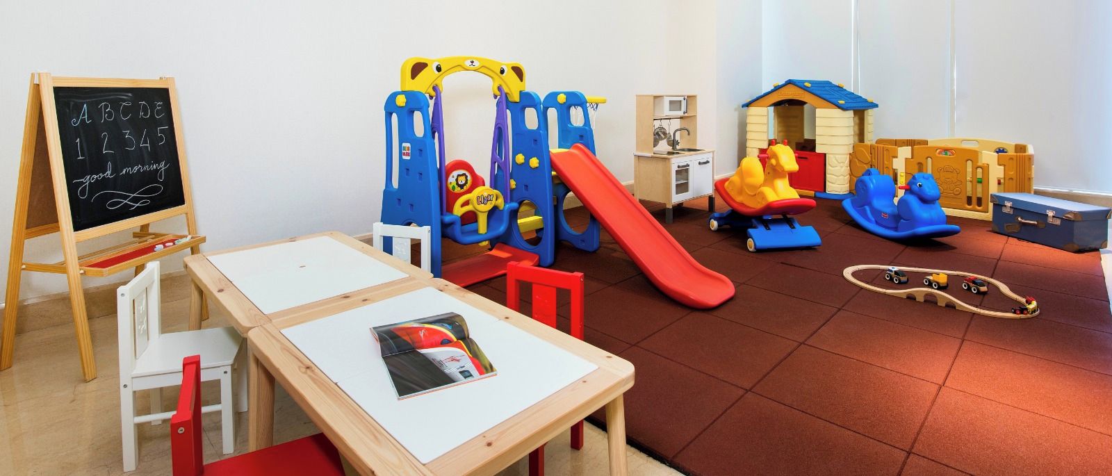 Un área de juegos infantiles con un tobogán, una estructura de escalada y un set de cocina de juguete.