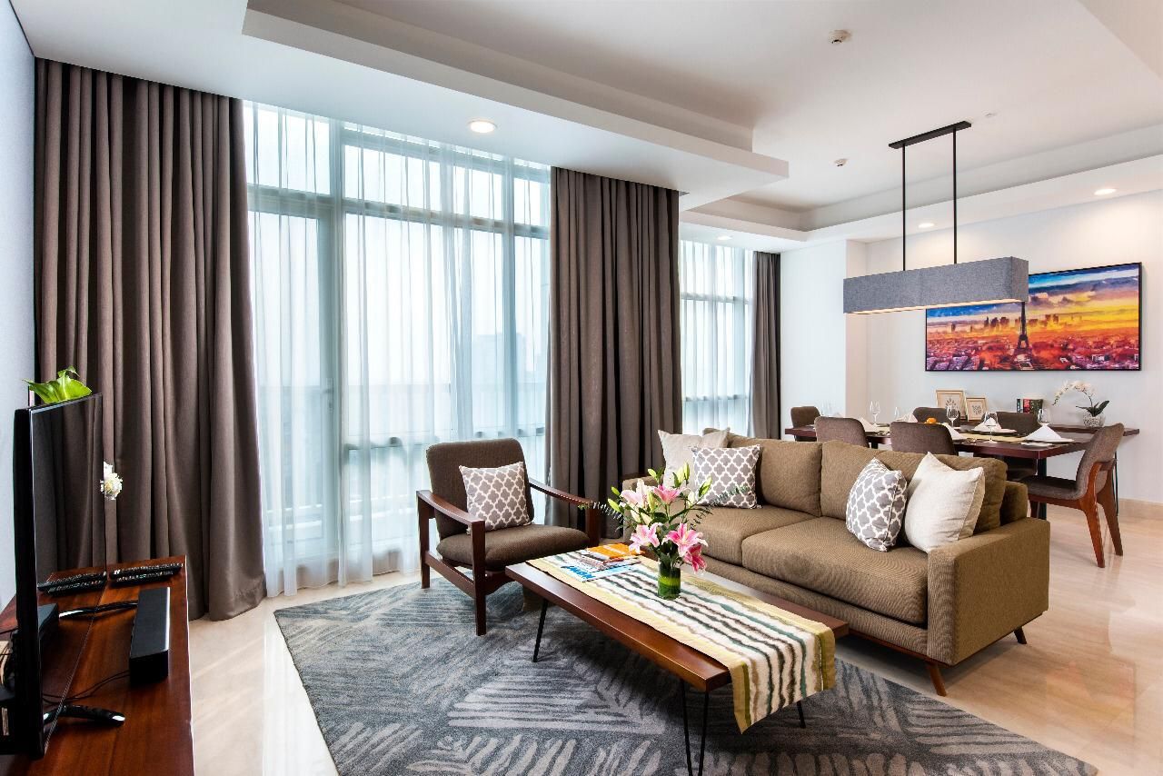 Una sala de estar moderna con un sofá, sillones, una mesa de centro y un televisor.