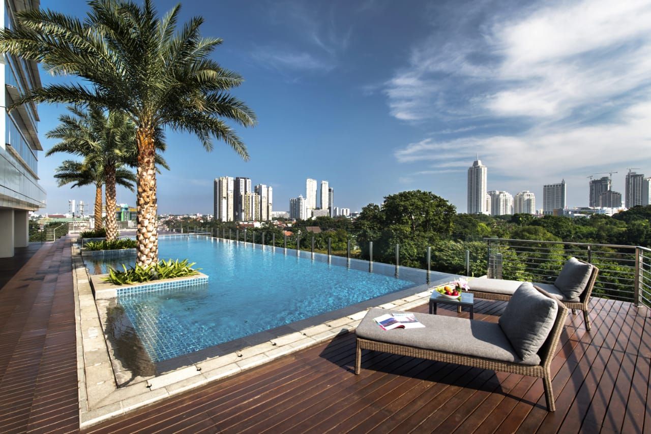 Una piscina en la azotea con sillones de descanso y vistas a un horizonte urbano.