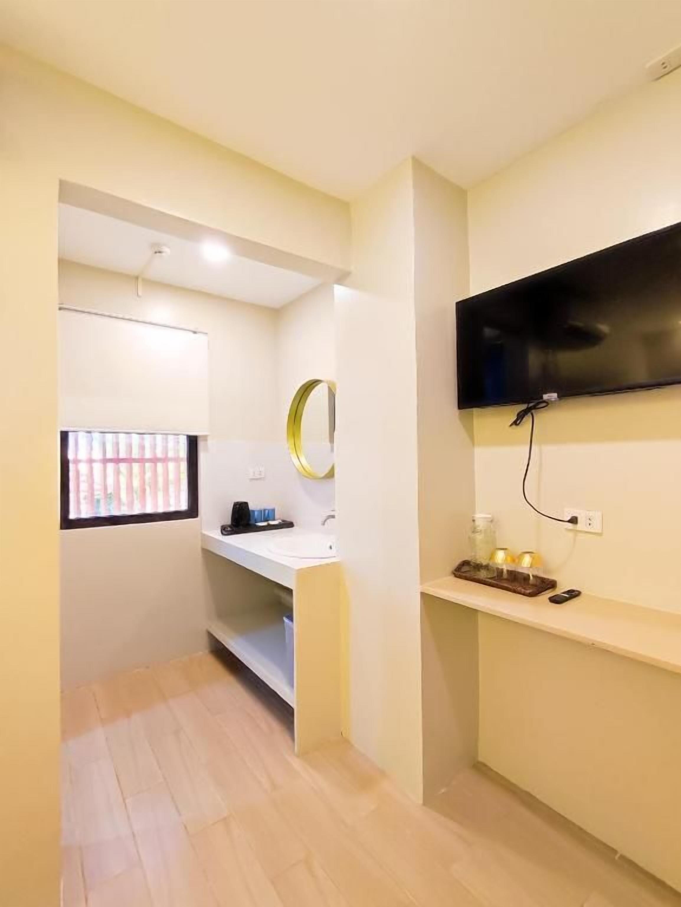 A small bathroom with a mirror, sink, and a television mounted on the wall.