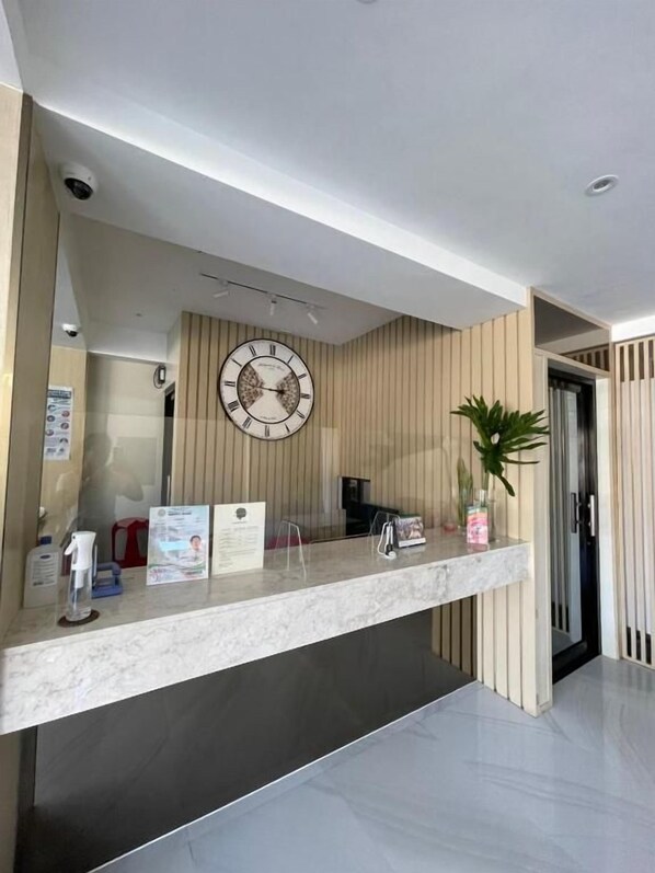 A reception desk with a clock, a plant, and informational brochures.
