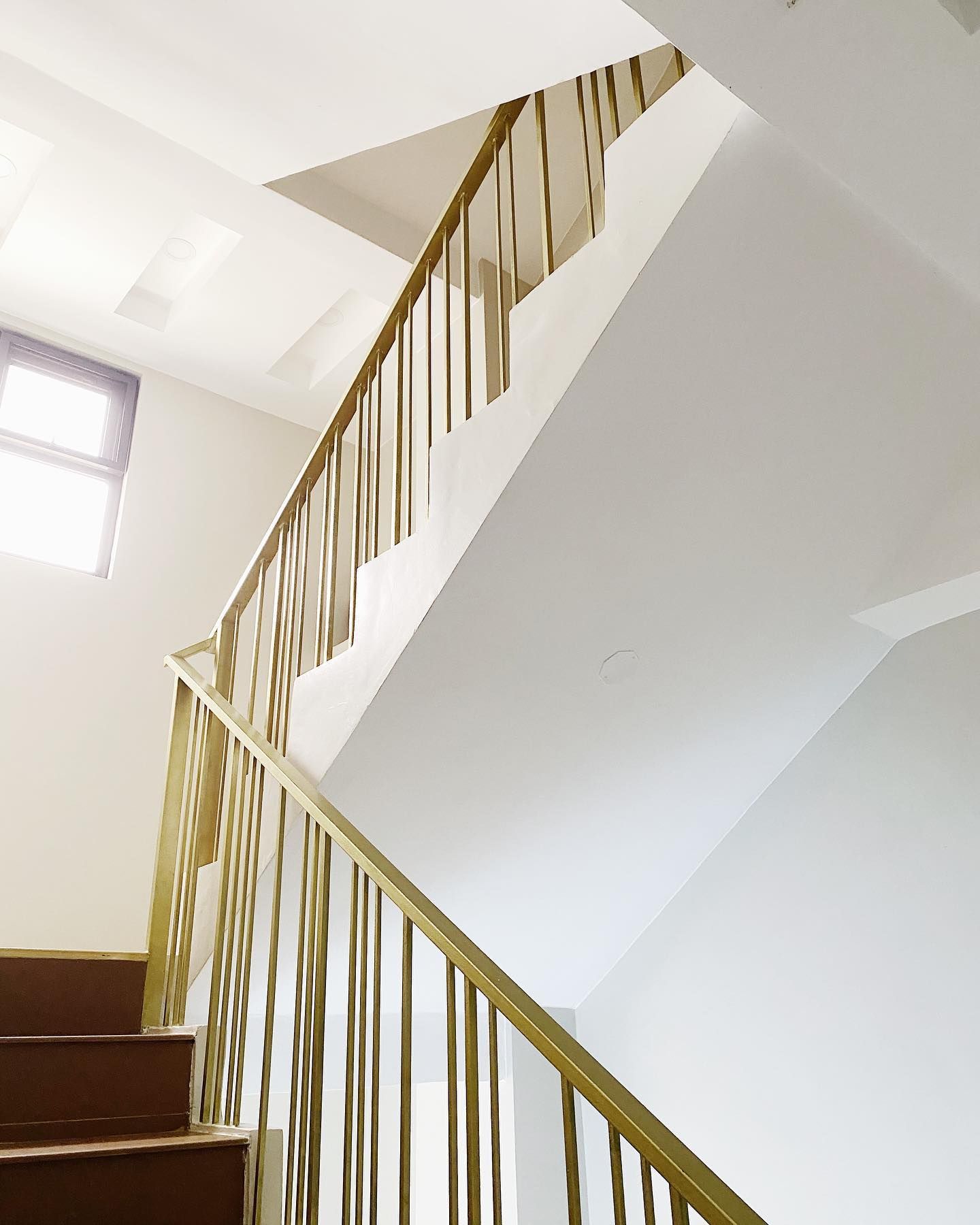 A staircase with a modern design, featuring a white wall and a wooden handrail.