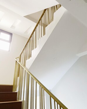A staircase with a modern design, featuring a white wall and a wooden handrail.