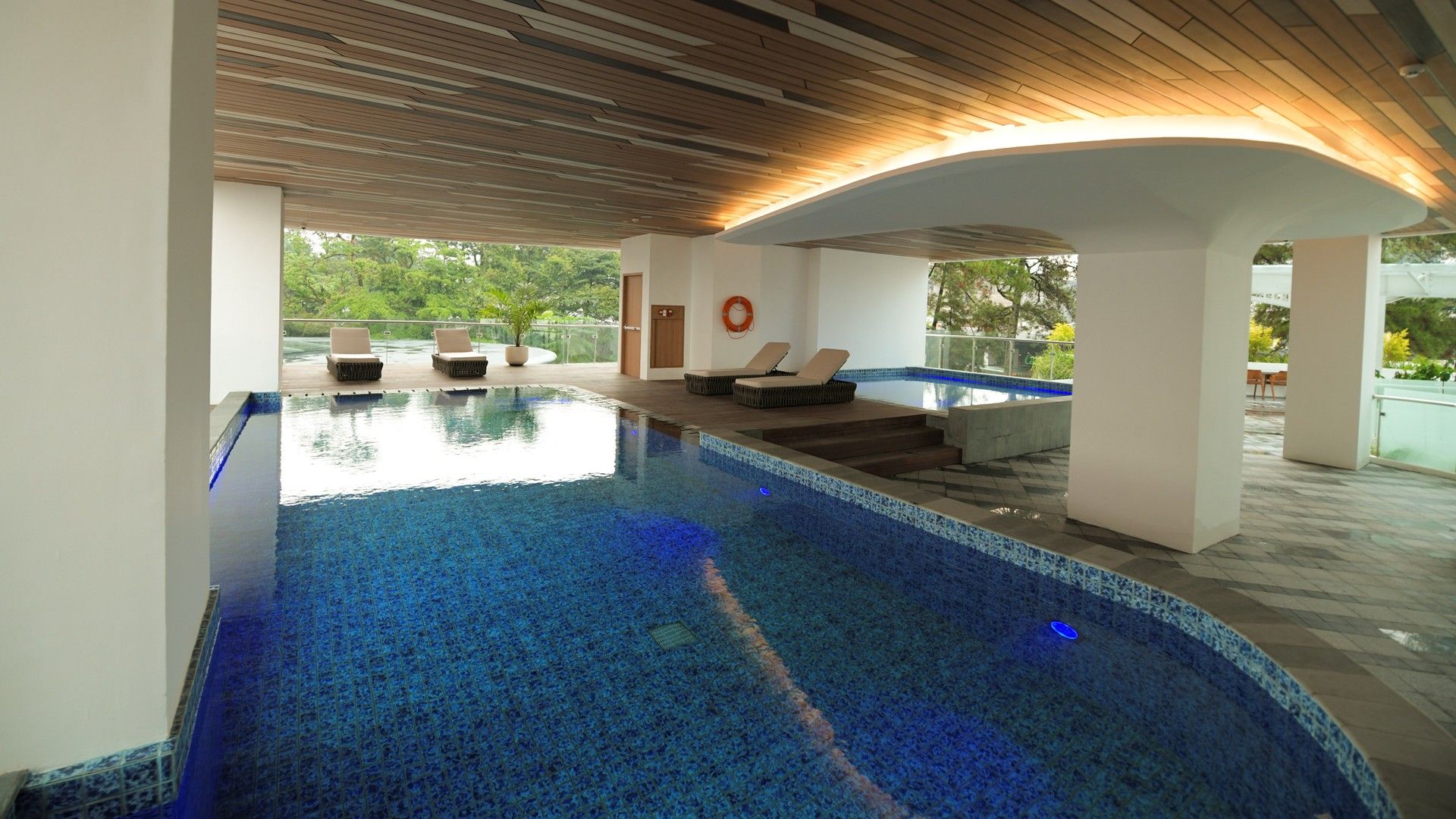 Una piscina interior con sillas de descanso y vistas a zonas verdes.