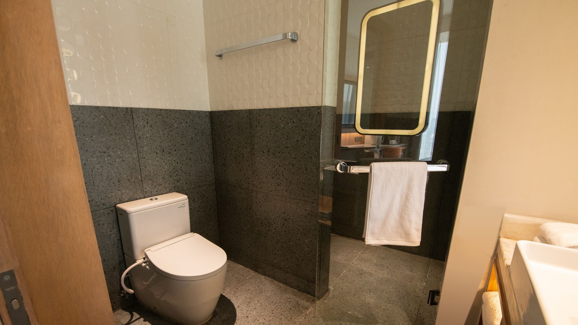 Un baño pequeño con inodoro, espejo y toallero.