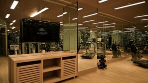 A hotel gym with mirrored walls, exercise equipment, and a reception desk.