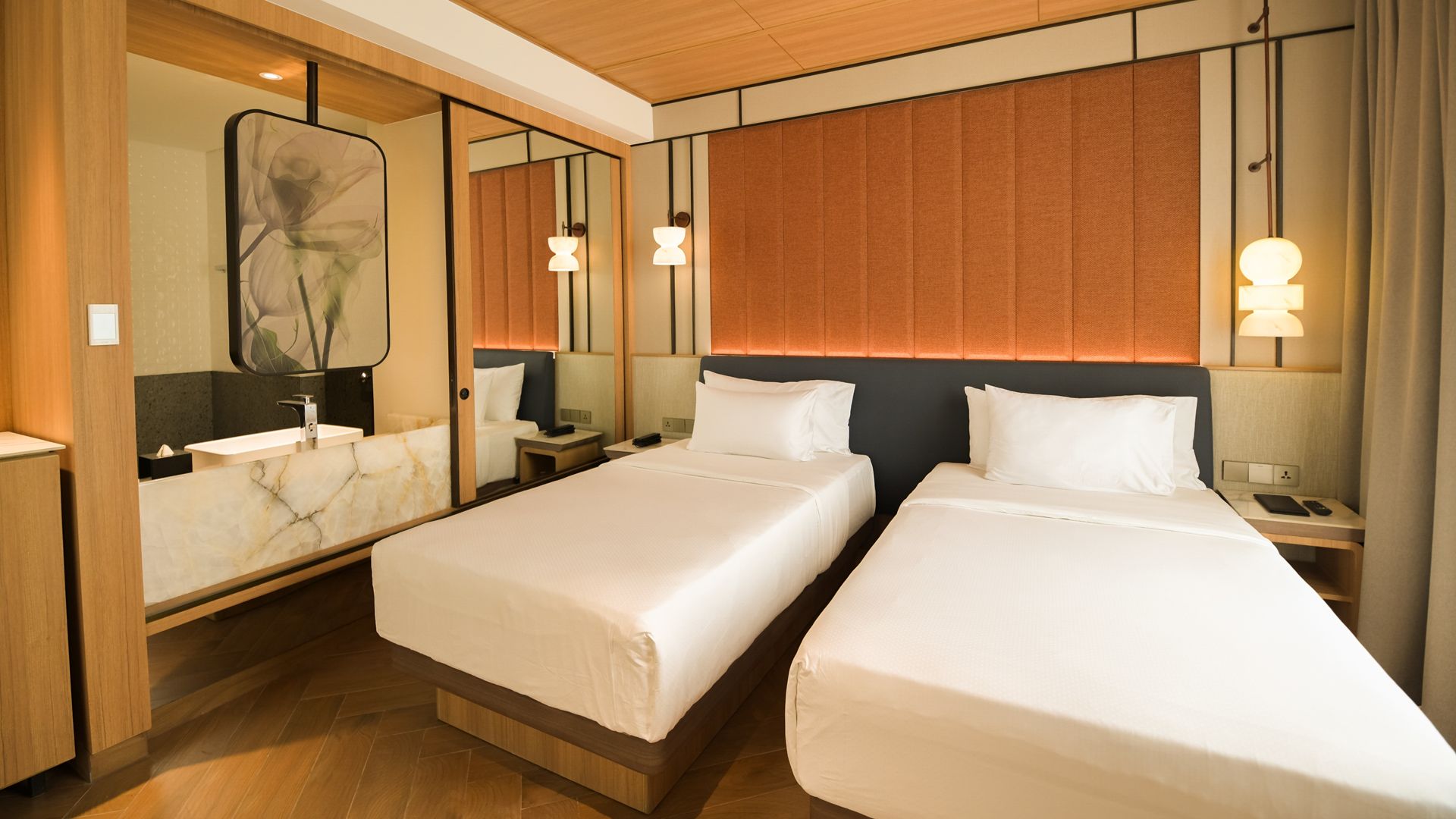 Una habitación de hotel con dos camas, un espejo grande y un cabecero de madera.