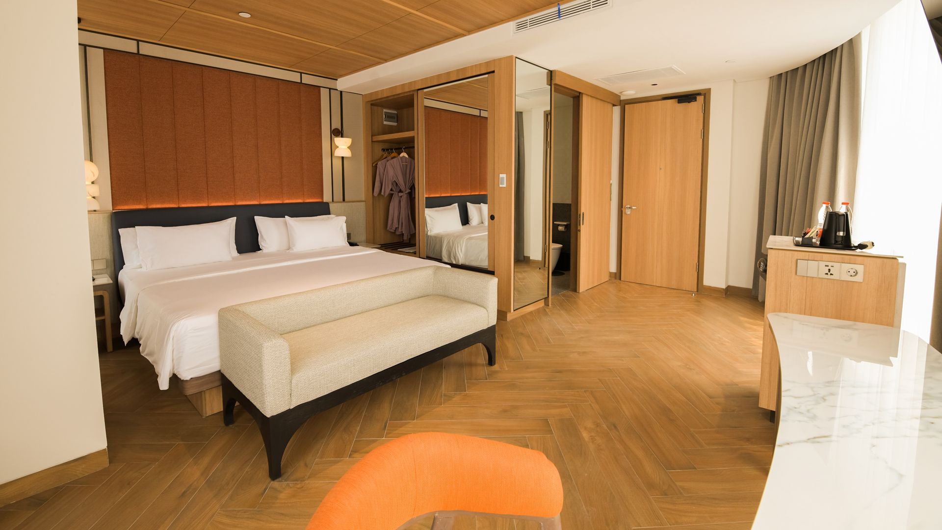 Ein Hotelzimmer mit einem großen Bett, einem Schreibtisch, einem Stuhl und einem Kleiderschrank.