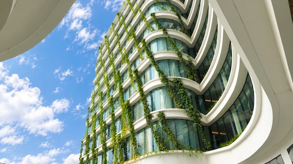 Un edificio moderno con balcones curvos y enredaderas verdes.