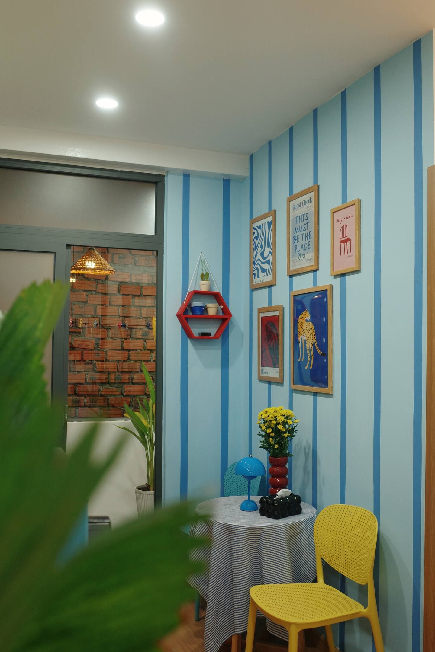 A room with a brick wall, a blue-striped wall, and a table with a striped tablecloth.