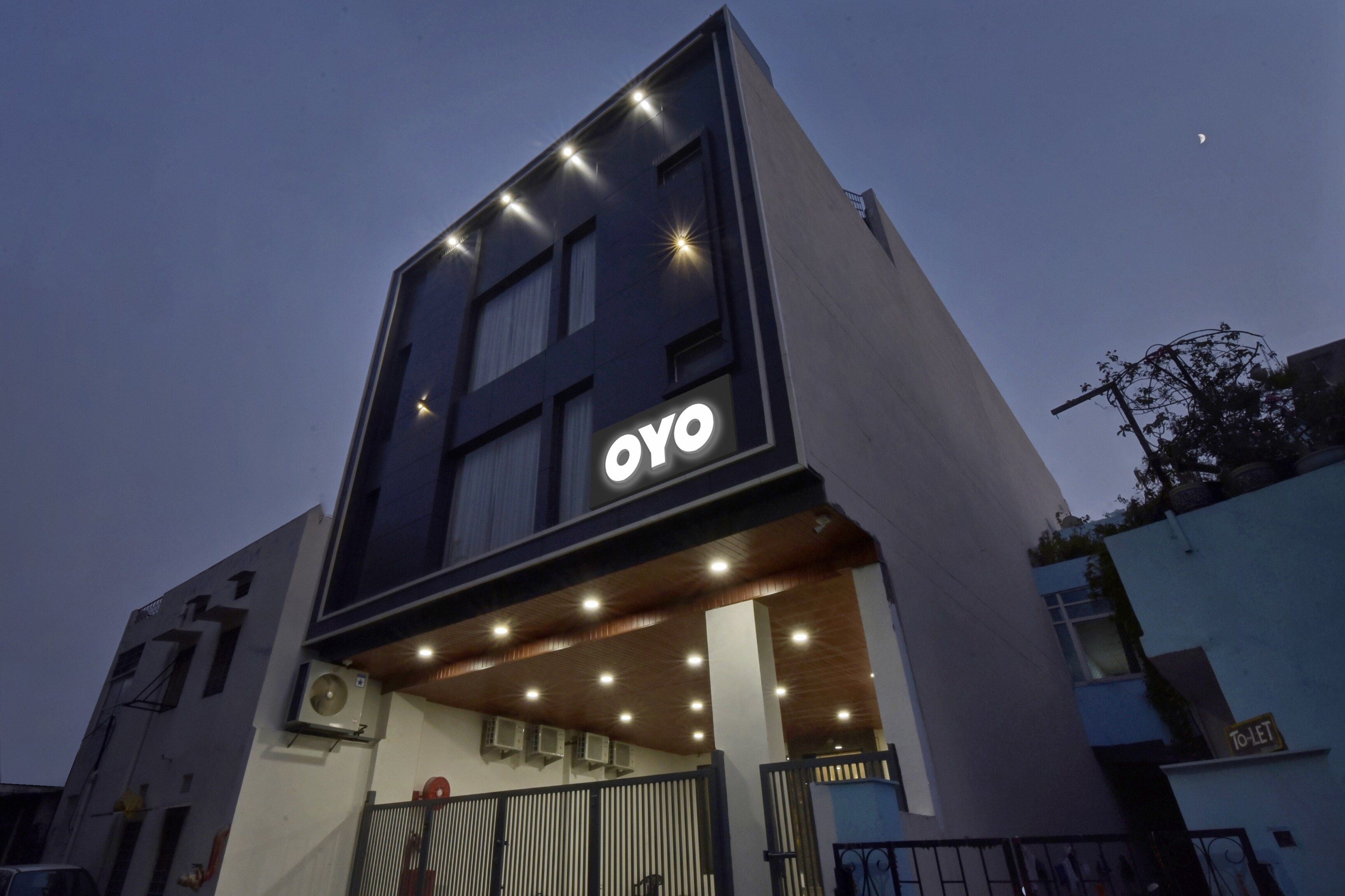 Un edificio moderno con un llamativo letrero de 'OYO' en la fachada, que indica que es un hotel.