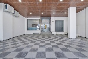 Un espacio interior amplio con suelo a cuadros, techo de madera y ventanas grandes.