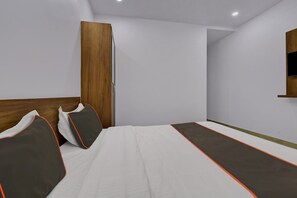 Un dormitorio con una cama, almohadas, un armario de madera y una estantería de pared.