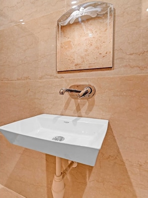 Ein Badezimmer mit einem weißen Waschbecken, einem Handtuchspender und einem Spiegel.