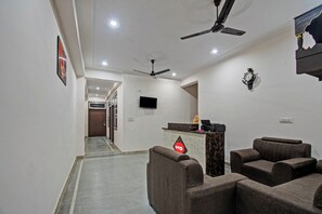 A hotel lobby with seating, a reception desk, ceiling fans, and a flat-screen TV. - Hotel O by OYO Shree Shyam Palace (Jaipur)