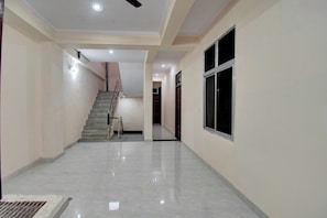 A hallway with a staircase, a window, and a ceiling fan. - Hotel O by OYO Shree Shyam Palace (Jaipur)