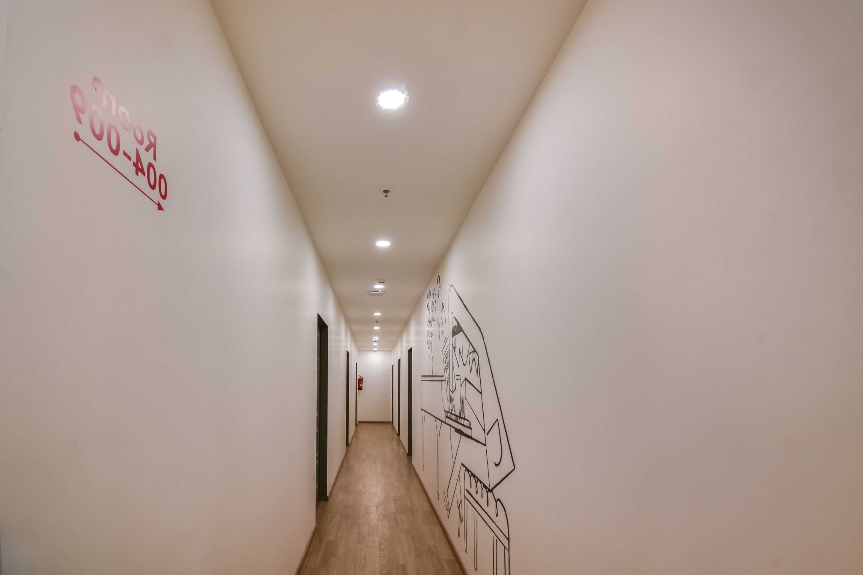 Un pasillo con suelo de madera, paredes blancas e iluminación empotrada en el techo.