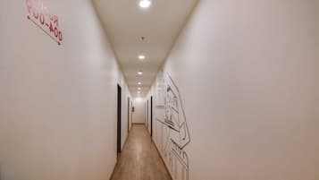 Un pasillo con suelo de madera, paredes blancas e iluminación empotrada en el techo.