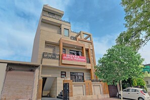 A multi-story hotel with a prominent sign for 'HOTEL JAIPUR PARADISE' advertising deluxe rooms and event hosting. - Hotel O The Castle Home Stay Inn (Jaipur)