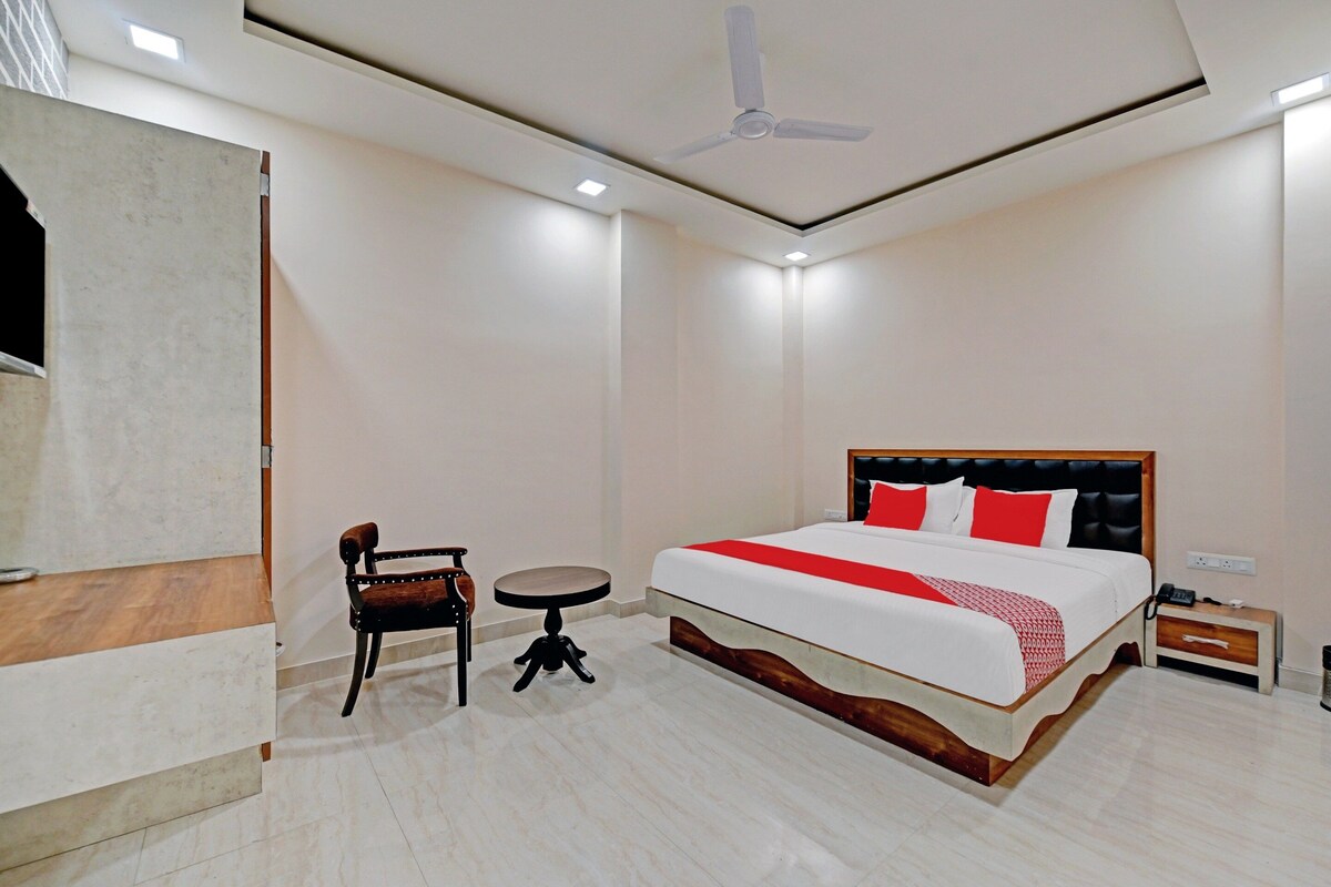 A hotel room with a bed, a chair, a small table, and a ceiling fan.
