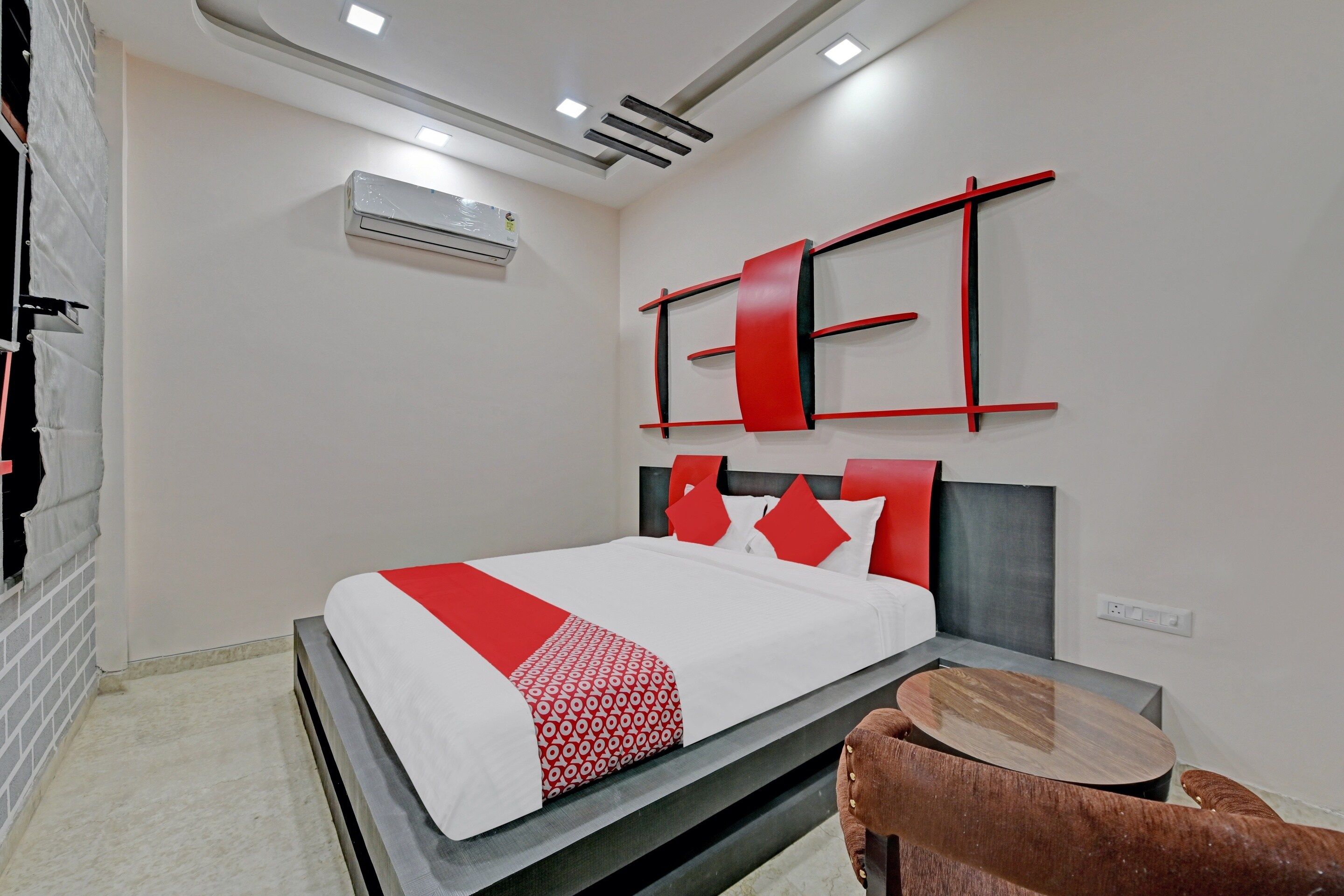 A modern hotel room with a bed, a small round table, and a wall-mounted air conditioning unit.