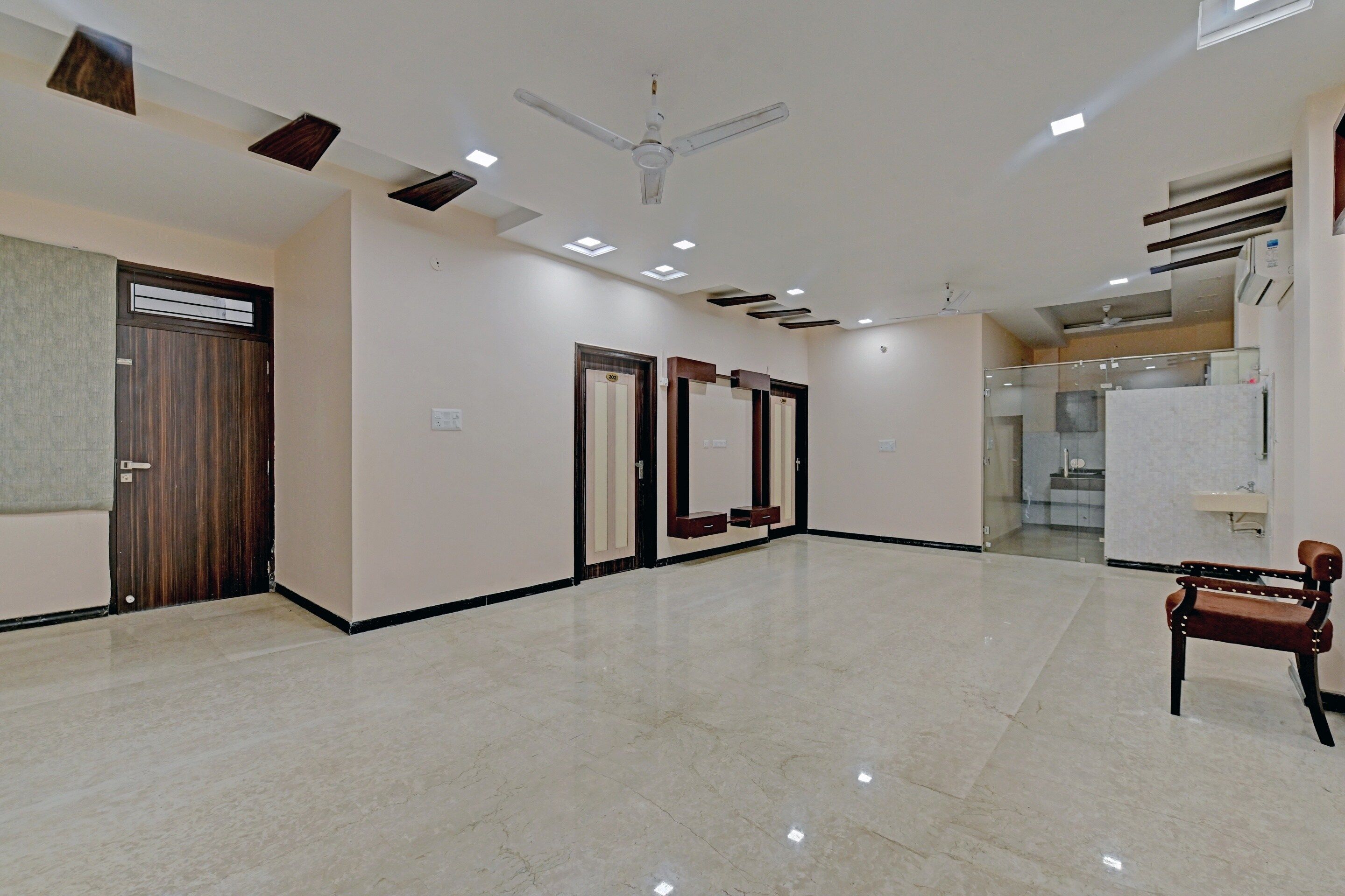 A spacious, well-lit hallway with a ceiling fan, recessed lighting, and a door leading to a bathroom.