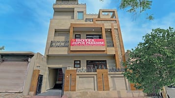 Un hôtel doté d’une enseigne bien visible indiquant « HÔTEL JAIPUR PARADISE », et qui propose des chambres de luxe, ainsi que des services pour l’organisation de mariages et de fêtes.