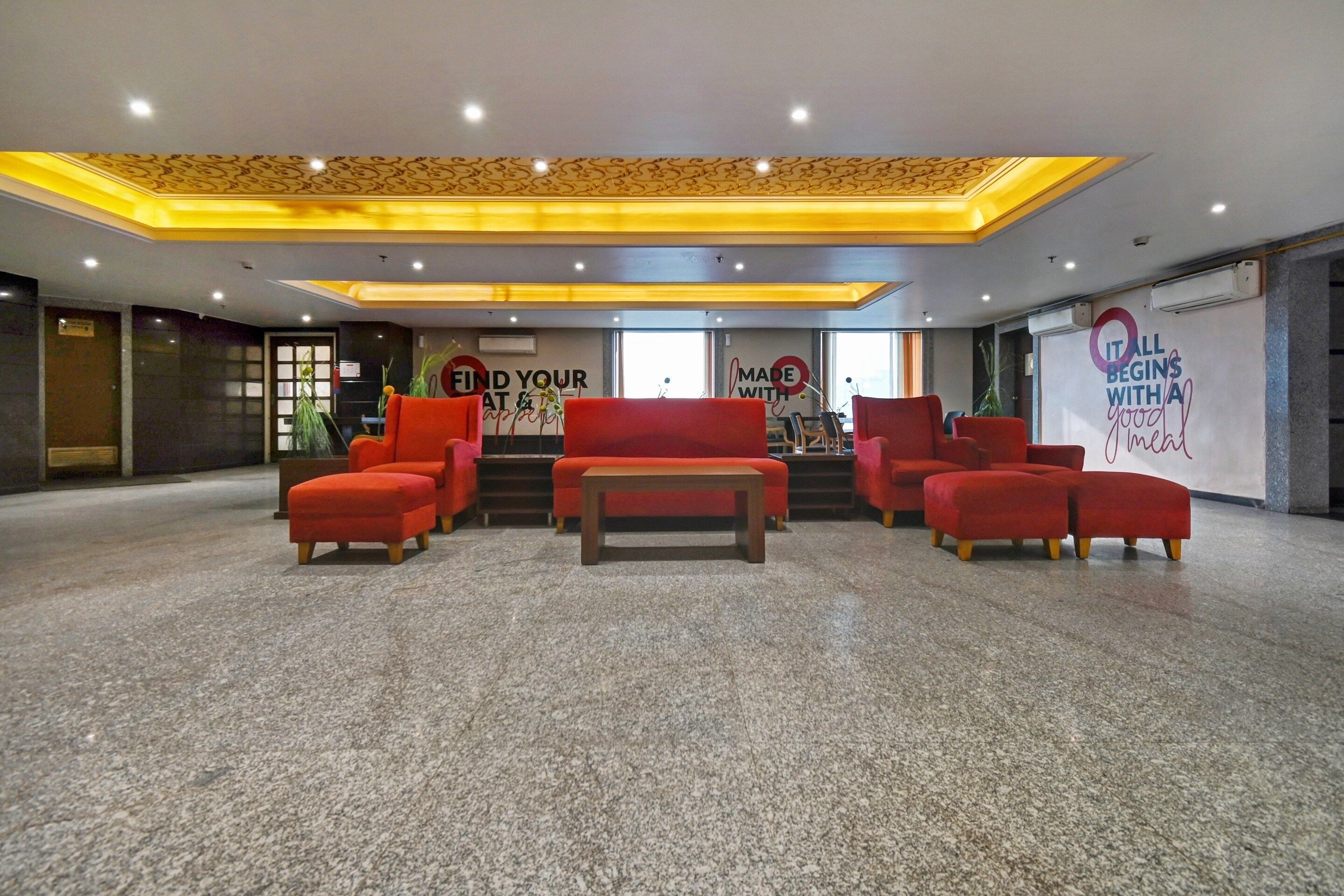 A lobby area with red seating, a staircase, and a banner stating 'All begins with a good meal.'