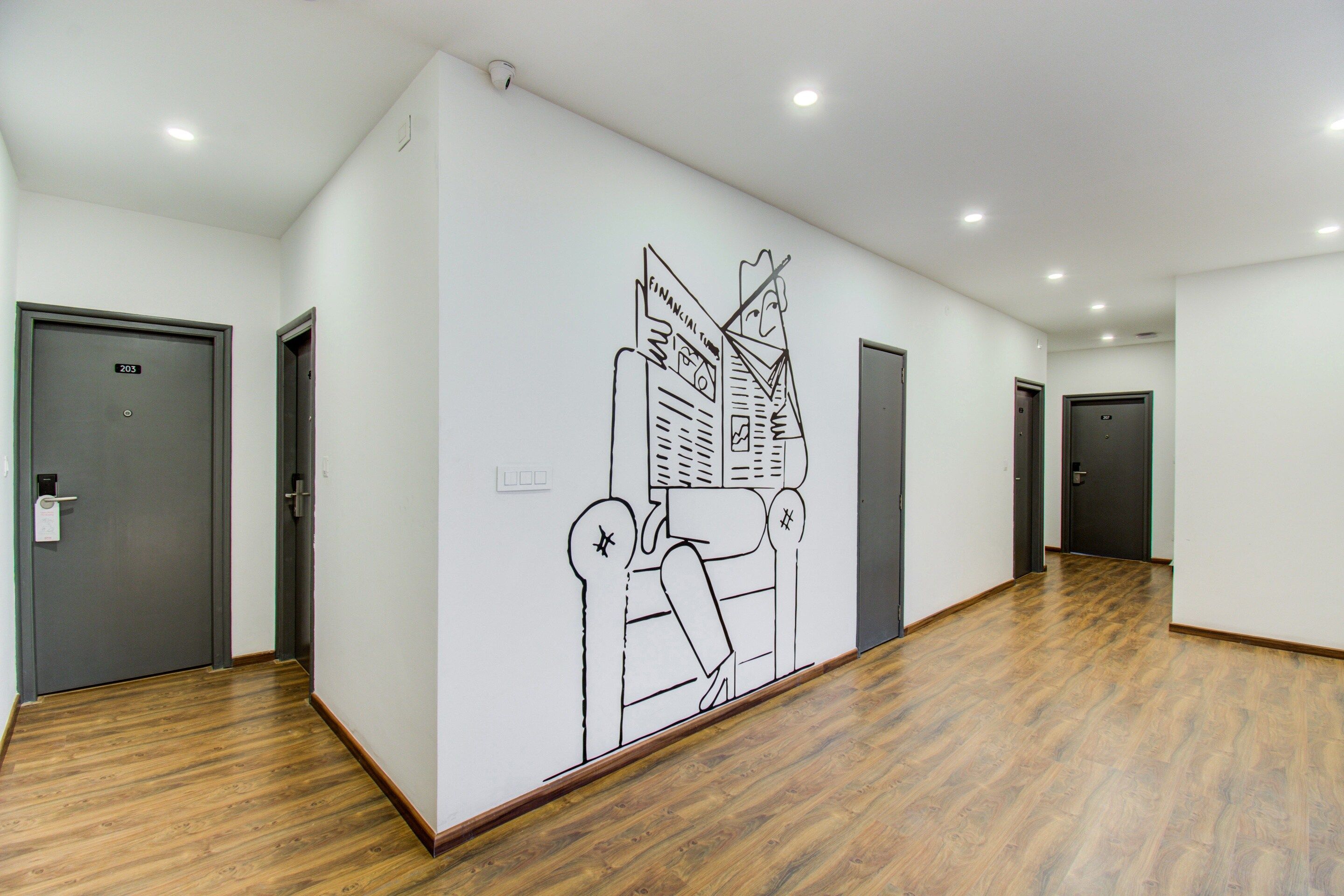 A hallway with wooden flooring, grey doors, and a large wall mural.
