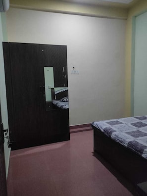 Een kamer met een bed, een deur en een spiegel aan de muur.