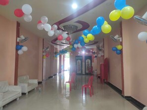 A hallway with a ceiling decorated with balloons, a chandelier, and a row of white sofas on the left. - Hotel O Pandit Siyaram Guest House (Bah)