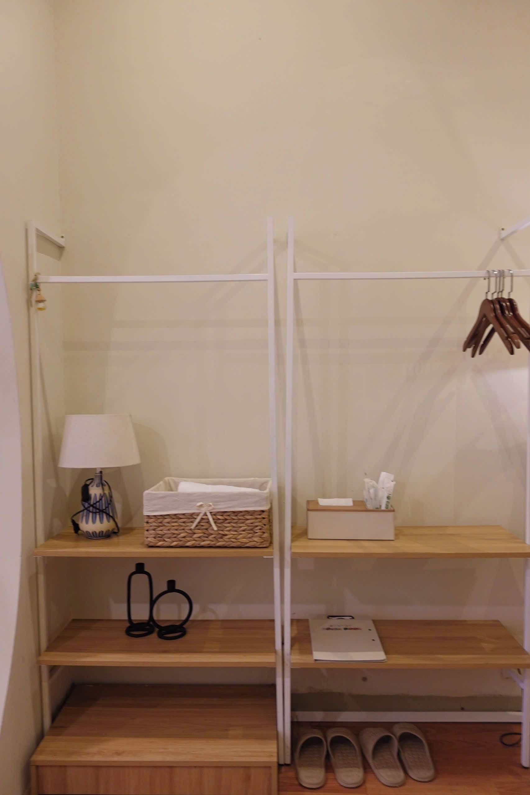 Una estantería de madera con una lámpara, una cesta y una caja de pañuelos.