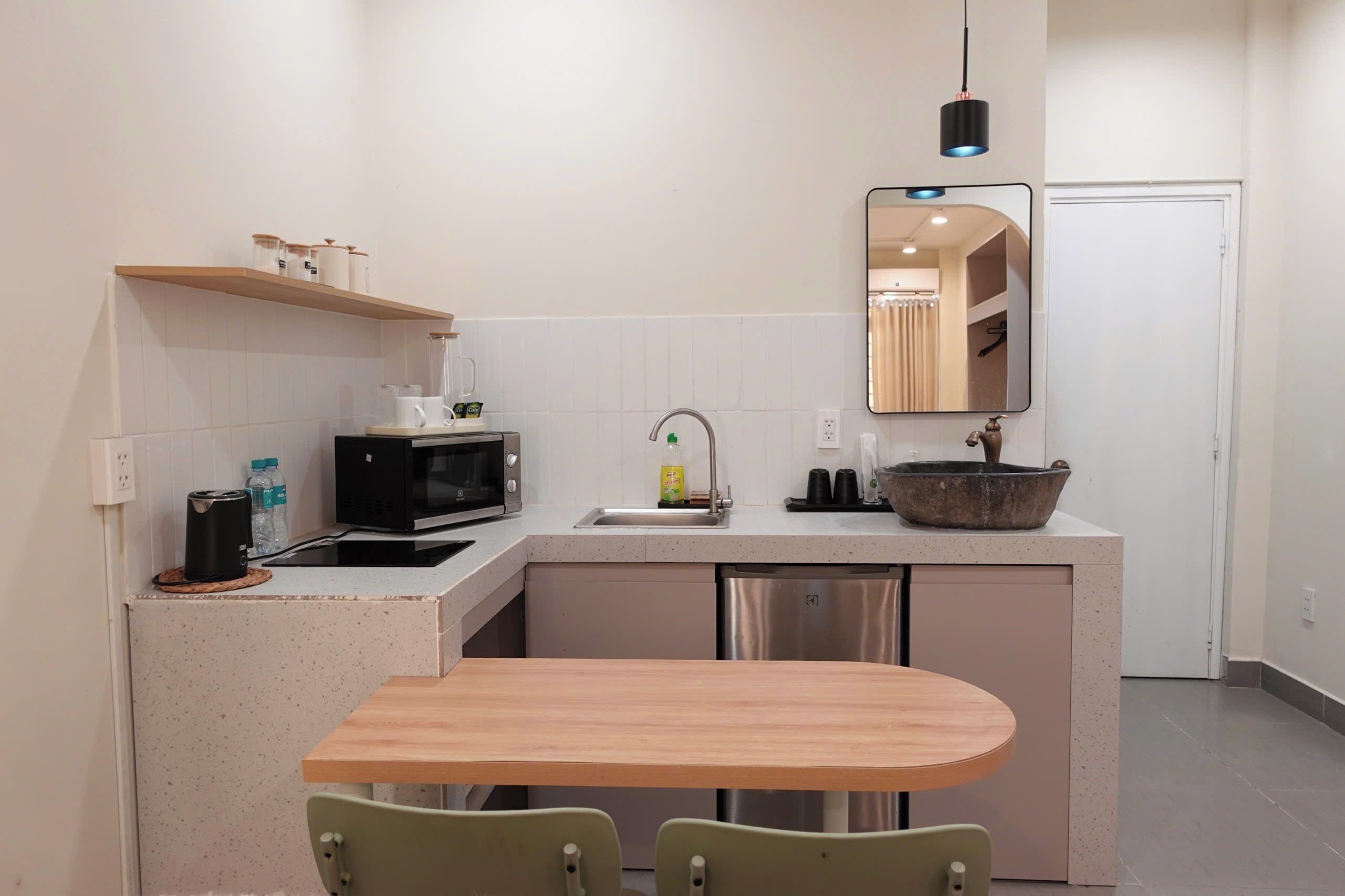 Una cocina compacta con microondas, pileta y un pequeño comedor con dos sillas.