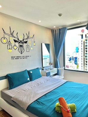 Ein modernes Hotelzimmer mit Bett, Schreibtisch, Spiegel und Blick auf die Stadt.