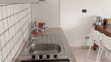 A kitchen with a gas stove, a sink, and a dining area with a table and chairs.