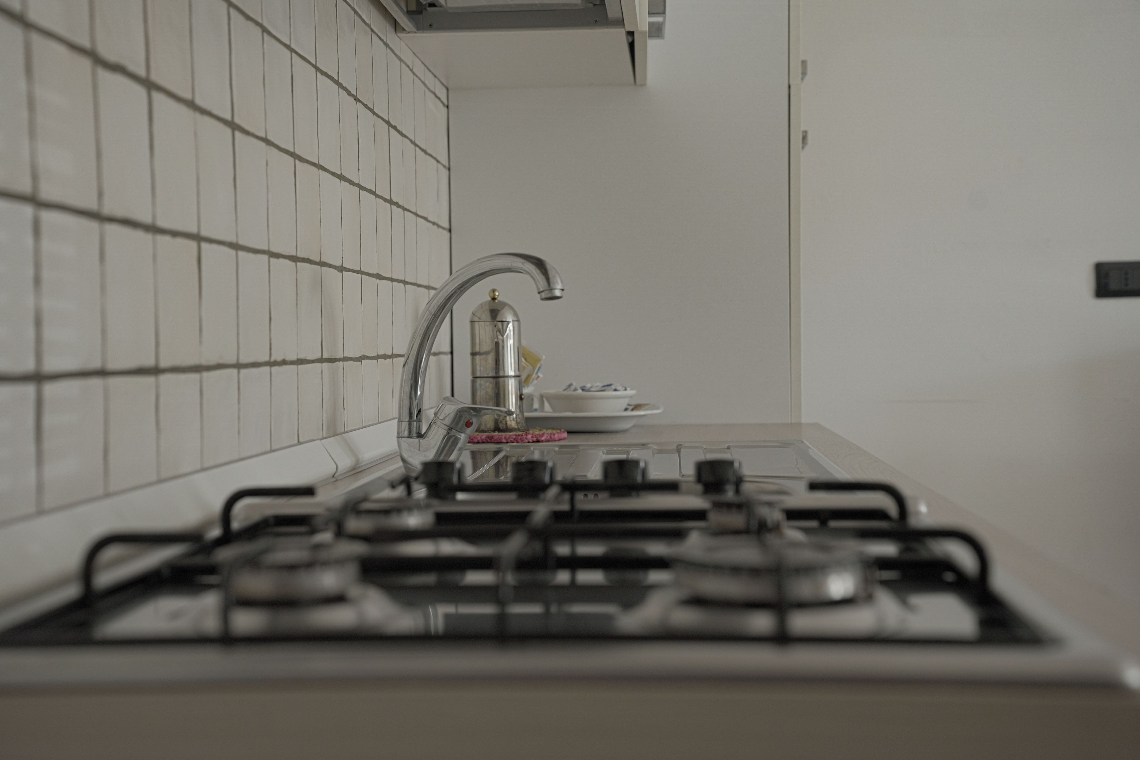 Una cocina con estufa a gas, un grifo moderno y salpicadero de azulejos.